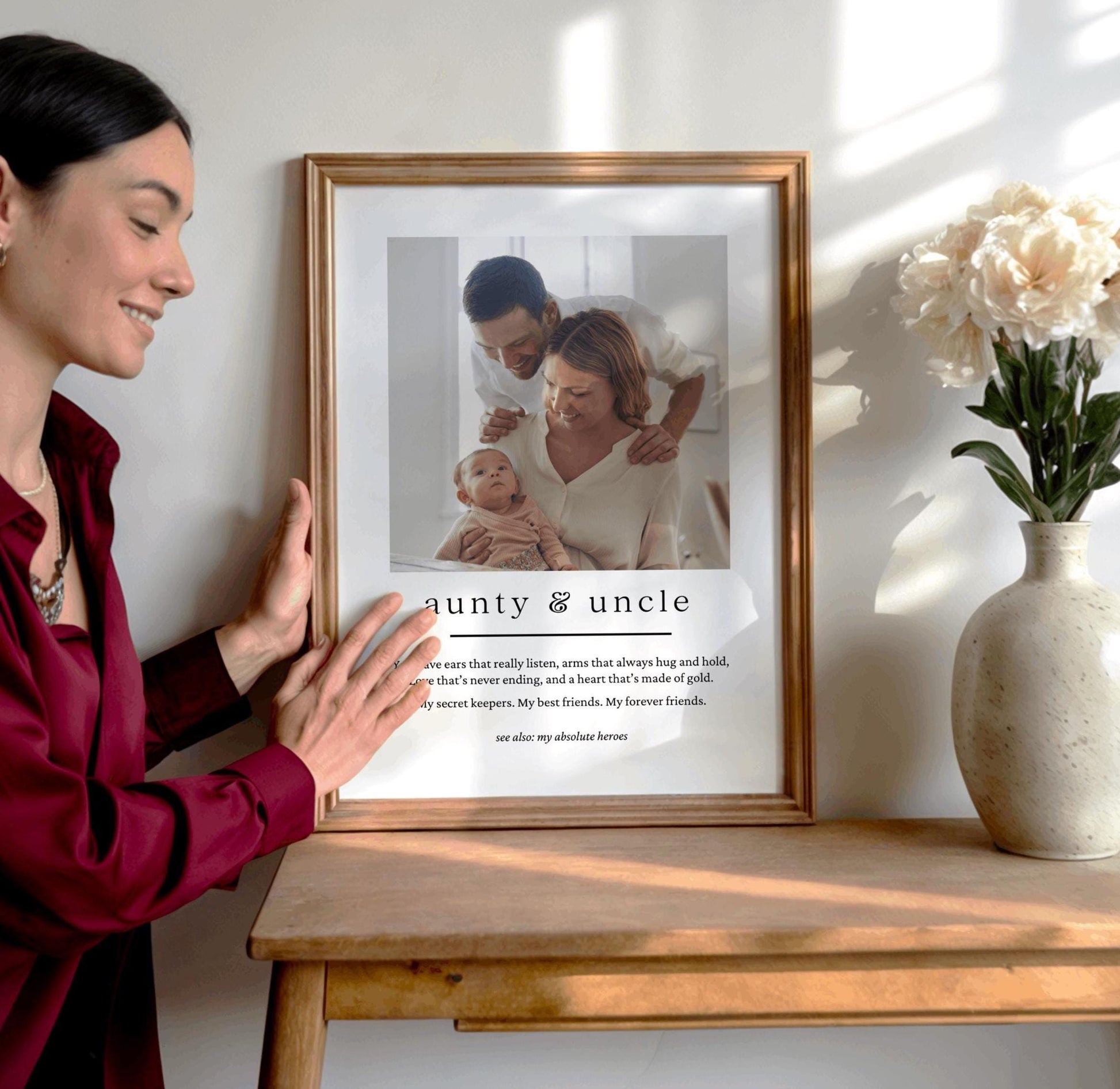 Woman holding a framed photo of a family with a baby on a wooden table.